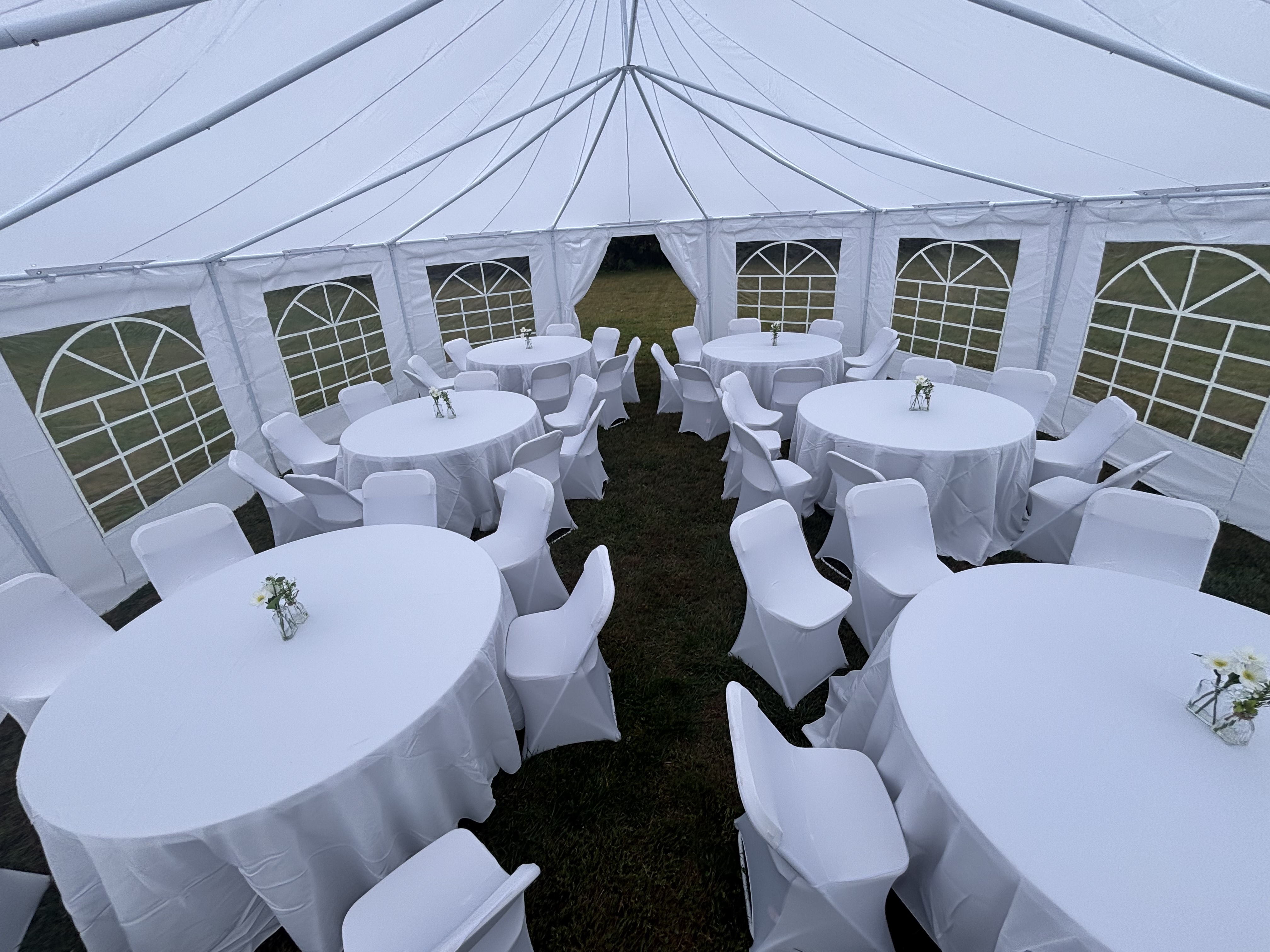 Interior of 29x23 tent with round tables, white linens and chair covers