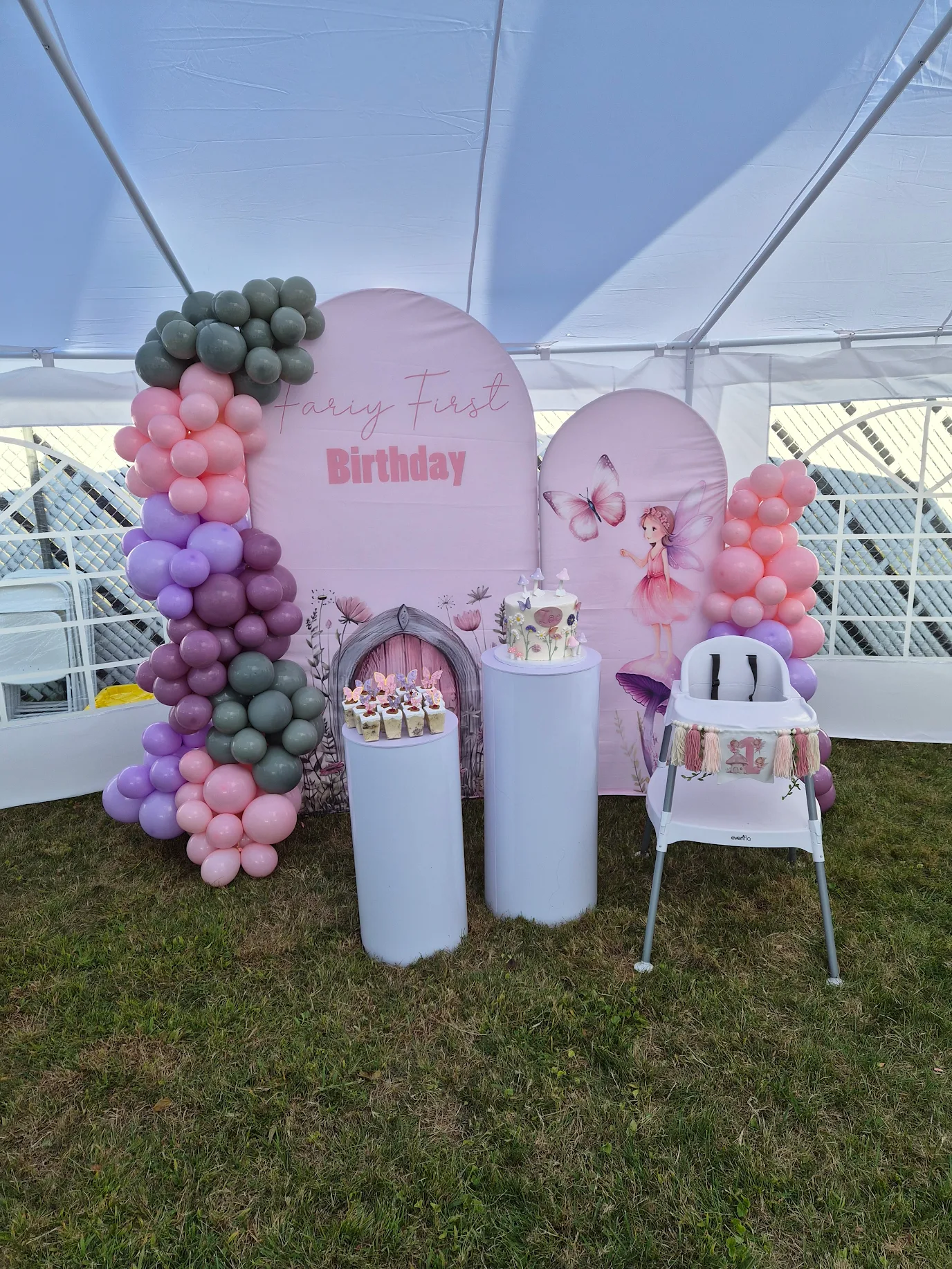 Fairy first birthday balloon arch and cake display inside a tent